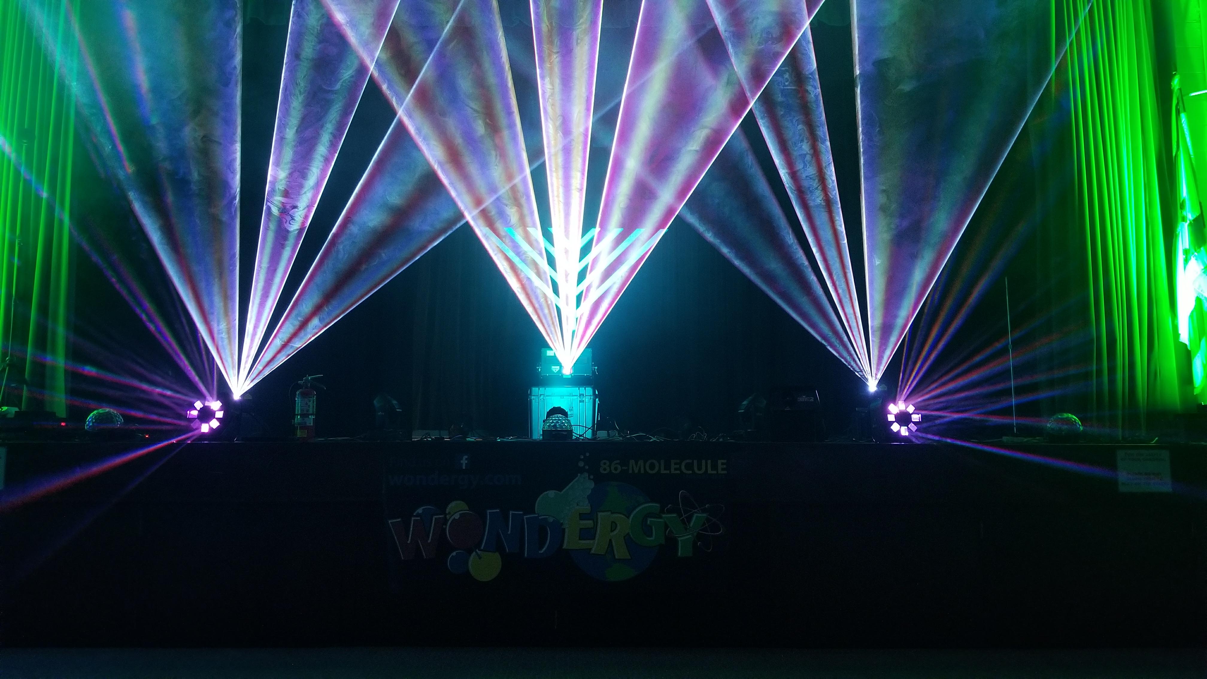 Symmetric fans of colored laser light fill a darkened hall