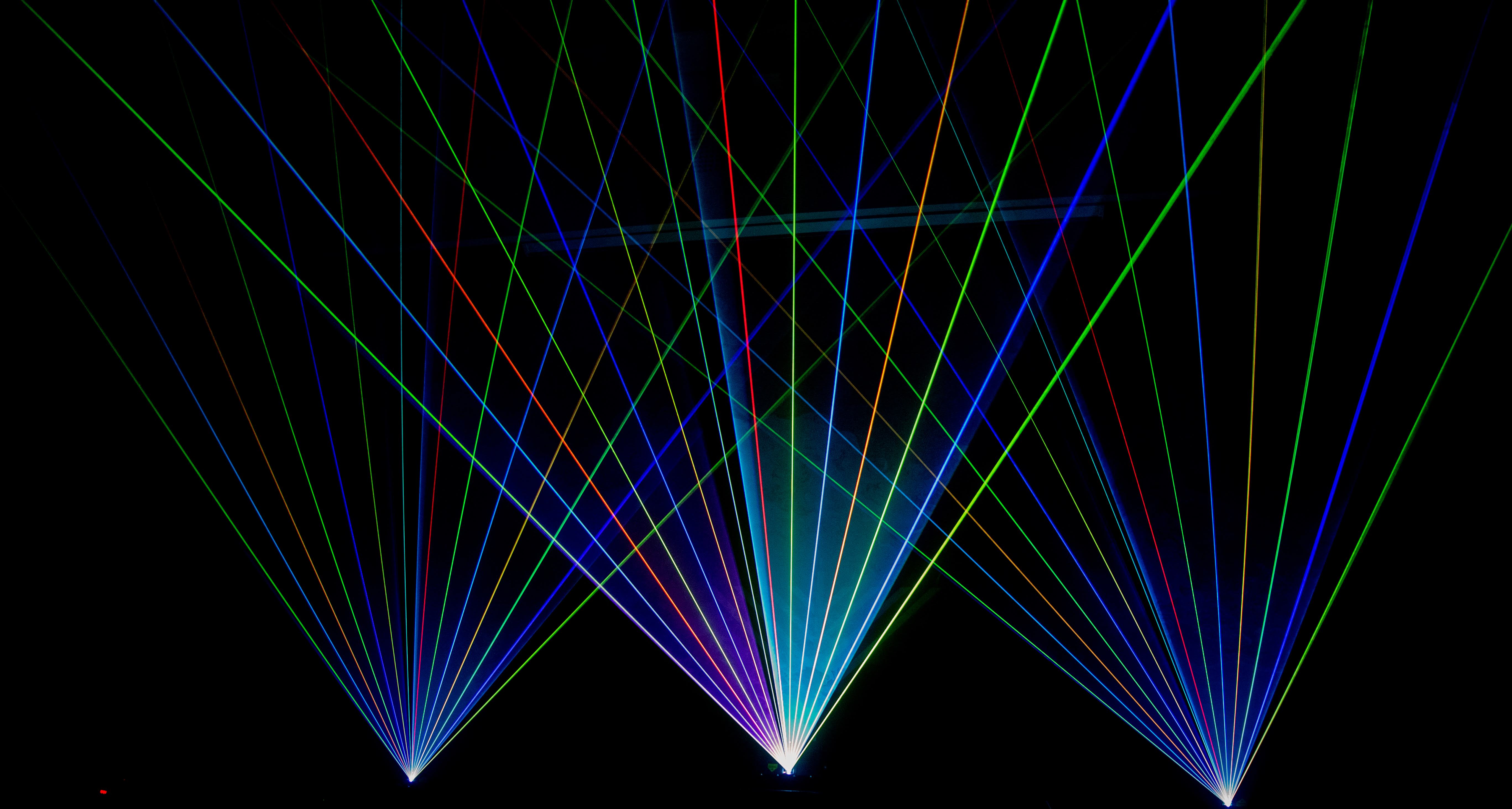 Symmetric green, blue and red laser fans converging in the dark at a Wondergy show